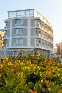 ein hohes weißes Gebäude mit vielen Fenstern in der Unterkunft Hotel Baia Imperiale in Rimini