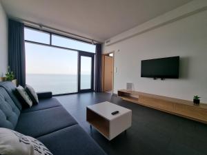 een woonkamer met een blauwe bank en een flatscreen-tv bij Boulevard - 365PAM in Ustronie Morskie