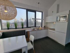 cocina con armarios blancos, mesa y ventanas en Boulevard - 365PAM, en Ustronie Morskie
