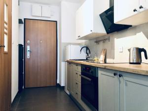 a kitchen with white cabinets and a wooden door at Blue River - Walonska 9 - private Apartment in Wrocław