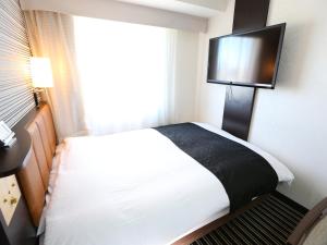 Cette chambre comprend un lit et une télévision à écran plat. dans l'établissement APA Hotel Higashi-Shinjuku-Ekimae, à Tokyo