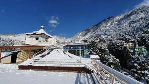 um edifício coberto de neve no topo de uma montanha em Nomadic Inn em Dharamshala