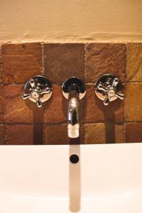 a bathroom sink with two knobs on a brick wall at Swellendam Self Catering in Swellendam