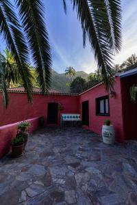 una casa roja con un patio de piedra con un banco en Casa Rural Abuelo Ramón, en Vallehermoso