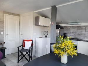 a kitchen with a table with a vase of yellow flowers at Chalet ALOHA in Saint-Côme-de-Fresné