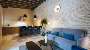 a living room with a blue couch and a kitchen at Magno Apartments Rocío in Seville
