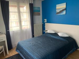 um quarto azul com uma cama e uma parede azul em Au Vieux Puits em Villers-Bocage