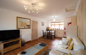 a living room with a couch and a tv at Surlingham Lodge Garden Cottage in Norwich