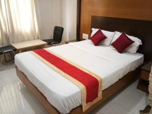 a bedroom with a large bed with a red and white blanket at HLVGRANDINN in Bangalore +33 photos