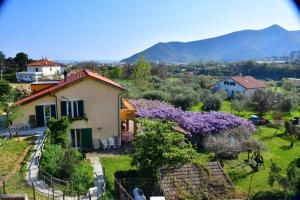 a small house with purple flowers in a yard at B&B La casa dei gelsi in Loano