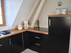 - une cuisine avec des armoires noires et un réfrigérateur noir dans l'établissement Gîte L'Arquebuse, à Troyes