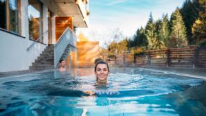 a woman is swimming in a swimming pool at Hotel Trattlerhof in Bad Kleinkirchheim