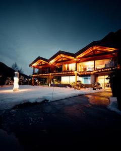 uma grande casa de madeira com neve em frente em Au Club Alpin em Champex