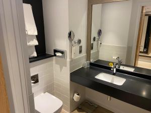 ein Badezimmer mit einem WC, einem Waschbecken und einem Spiegel in der Unterkunft Holiday Inn Lincoln, an IHG Hotel in Lincoln