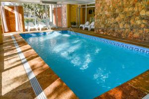 een groot zwembad met blauw water in een hotelkamer bij Casa Puente Albor PISCINA CLIMATIZADA in El Espinar