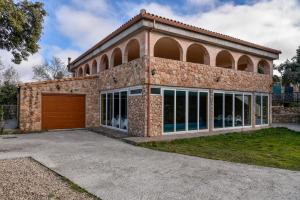 a large brick house with a garage at Casa Puente Albor PISCINA CLIMATIZADA in El Espinar