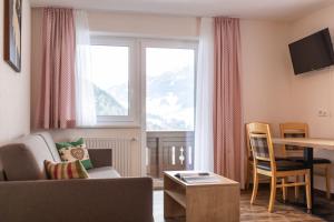 salon z kanapą, stołem i oknem w obiekcie Pitztal Living Apartments w mieście Jerzens