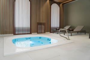 a jacuzzi tub in a room with two chairs at Hotel São Bento da Porta Aberta & Spa in Geres