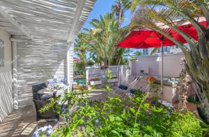 un patio con una mesa y una sombrilla roja en Apartment Melkbos Moments en Melkbosstrand