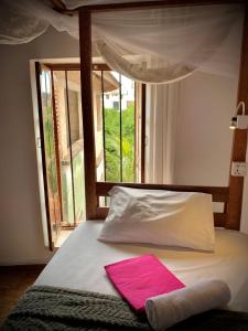 a bed with a pink pillow and a window at Stone Town House in Zanzibar City