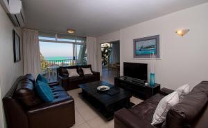 a living room with leather couches and a television at 17 Kyalanga Umhlanga Rocks in Durban