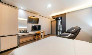 um quarto com uma cama, uma secretária e uma televisão em Hotel The May em Busan
