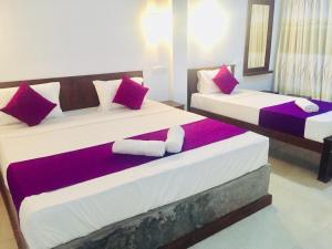 Duas camas num quarto com almofadas vermelhas e roxas em Cumini Resort em Anuradhapura