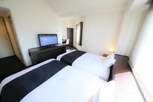 a hotel room with two beds and a flat screen tv at APA Hotel Sagamihara Hashimoto Ekimae in Sagamihara