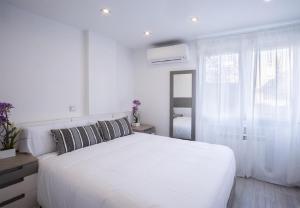 Un dormitorio blanco con una cama blanca y una ventana en Apartamento Avenida America Confort XIII en Madrid, en Madrid