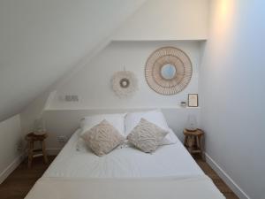 ein weißes Bett mit zwei Kissen und einem Spiegel in der Unterkunft Santorin, Appartement lumineux au coeur de Vannes in Vannes