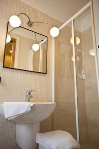 ein Bad mit einem Waschbecken und einer Dusche mit einem Spiegel in der Unterkunft Hotel Malibran in Venedig