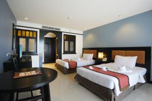 a hotel room with two beds and a table at Woraburi Phuket Resort & Spa - SHA Plus in Karon Beach