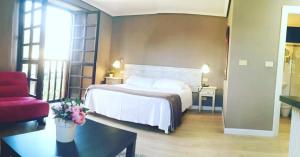 Habitación de hotel con cama y silla roja en Hotel Colegiata, en Santillana del Mar