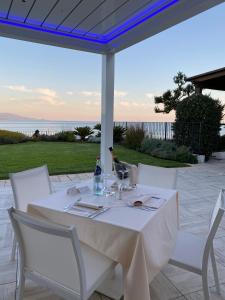 een witte tafel met witte stoelen en een fles wijn bij Hotel Punta Negra in Fertilia