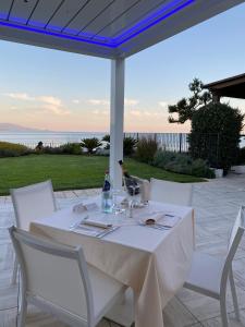 a white table with white chairs and a bottle of wine at Hotel Punta Negra in Alghero