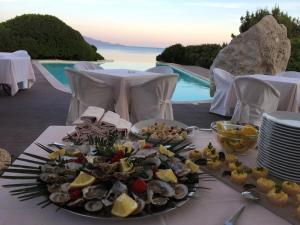 a plate of food on a table next to a pool at Hotel Punta Negra in Alghero