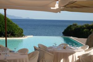 a pool with tables and chairs next to the water at Hotel Punta Negra in Alghero
