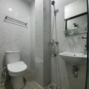 a white bathroom with a toilet and a sink at Circle One in Palembang