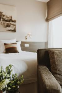 ein Hotelzimmer mit einem Bett und einem Stuhl in der Unterkunft Grand Hotel Belle Vue in De Haan