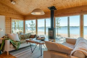 a living room with a fireplace and a view of the ocean at Utula Nature Retreat in Ruokolahti