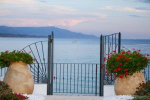 a gate with two large vases filled with red flowers at Hotel Punta Negra in Alghero