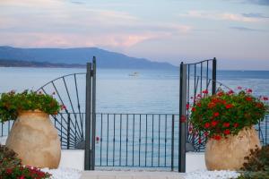 un cancello con due grandi vasi pieni di fiori rossi di Hotel Punta Negra a Fertilia