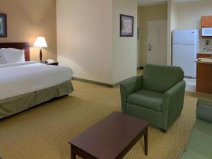 a hotel room with a bed and a chair at MainStay Suites Addison - Dallas in Addison