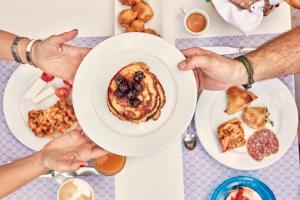 two people holding a plate of food on a table at Angelina Boutique Escape in Perdika