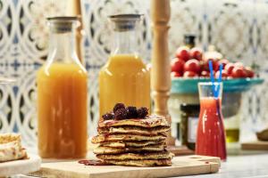 a stack of pancakes with fruit on a table with bottles of juice at Angelina Boutique Escape in Perdika
