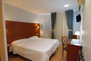 a hotel room with a bed, chair, and nightstand at Hotel Hispania in Zaragoza