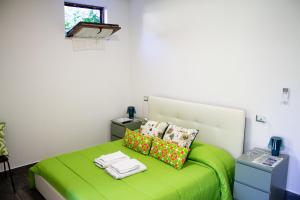 a bedroom with a green bed with pillows and a window at Bed and Breakfast La Palanzana in Viterbo