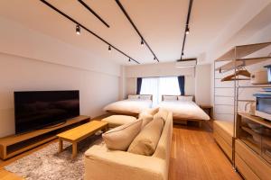 NIYS apartments 08 type في طوكيو: غرفة معيشة بها سريرين وأريكة وتلفزيون
