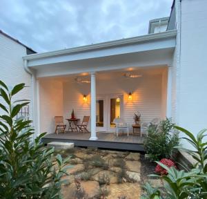Cette maison blanche dispose d'une terrasse couverte avec des chaises et une table. dans l'établissement Belle Louise Historic Bed & Breakfast, à Paducah