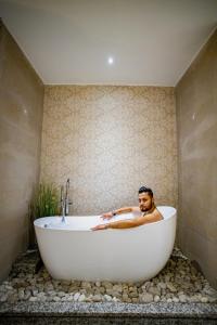 a man sitting in a bath tub in a bathroom at Arushi Boutique Hotel in Kathmandu